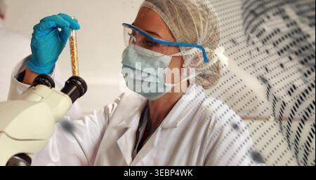 Inspektion von Technikern, die PSA tragen, mit gelber Probe im Labor mit binokularem Mikroskop Stockfoto