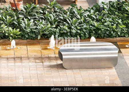 Moderner öffentlicher Raum mit Bänken, Springbrunnen und gefliestem Bürgersteig Stockfoto