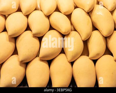 Nahaufnahme der Vollformatansicht frischer, reifer, süßer gelber Mangos, die ordentlich aufeinander gestapelt sind. Perfekt für tropische Früchte, gesunde Ernährung und frische Landwirtschaft Stockfoto