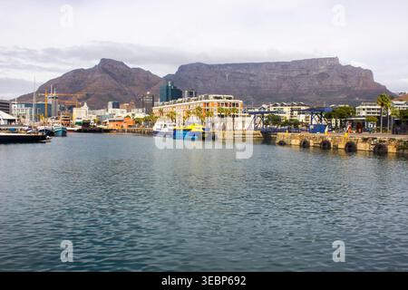 Blick auf die V&A-Uferpromenade am alten Hafen von Kapstadt mit Tafelberg im Hintergrund an einem bewölkten Tag. Stockfoto