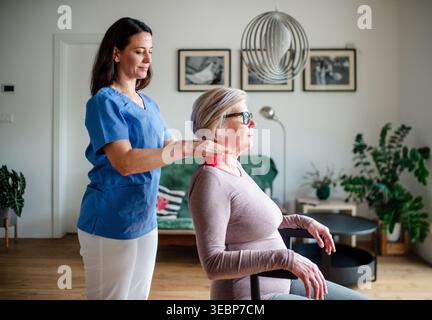 Pflegekraft hilft älteren Frauen bei Rehabilitationsübungen mit Massageball. Stockfoto