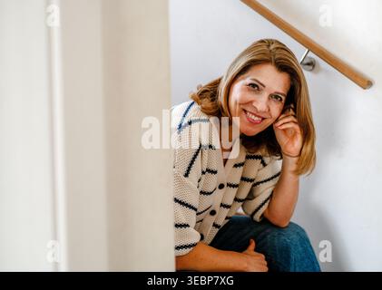 Schöne Frau, die sich ausruht, auf der Treppe sitzt. Stockfoto