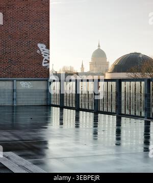 Stadtlandschaft: st. Nikolaikirche von einem nassen Parkhaus auf dem Dach. Nasse Asphaltreflektionen, Ziegelwände und Morgennebel. Stockfoto