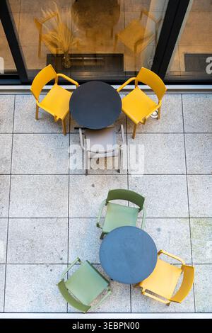 Blick von oben auf farbenfrohe leere Cafés auf einer gepflasterten Straße mit Kopierraum. Stockfoto
