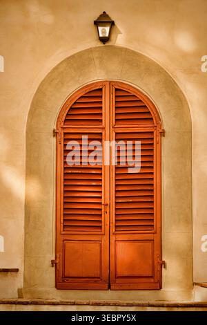 Architektur eines Eingangs, orangefarbene Shuttles, Torbogen, goldener Stuck und kleine Eingangslampe. Stockfoto