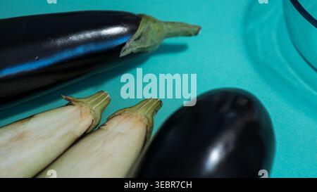 Ganze Auberginen und klare Glasschale auf blauem Hintergrund — Fresh Aubergine Flat Lay Food Photography Stockfoto