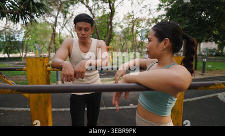 Zwei junge Fitnessbegeisterte, die während ihres Trainings in einem Park eine Pause einlegen Stockfoto