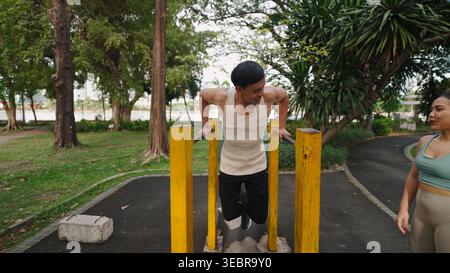Entschlossener Athlet, der mit Personal Trainer im Freien trainieren kann, verbessert die Kraft des Oberkörpers und die Fitness im Stadtpark Stockfoto