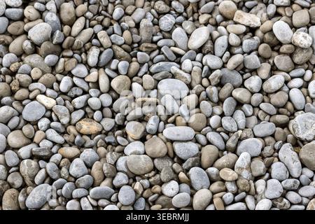Hochauflösende Vollformataufnahme von glatten, abgerundeten Meereskieseln in verschiedenen Grau-, Blau- und Brauntönen. Ein Natursteinhintergrund mit va Stockfoto