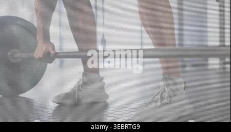 Packende Langhantel mit Stoßstangen, männliches Anheben auf Gummiboden im Fitnessstudio, sportliche Shorts, leichte Schuhe Stockfoto
