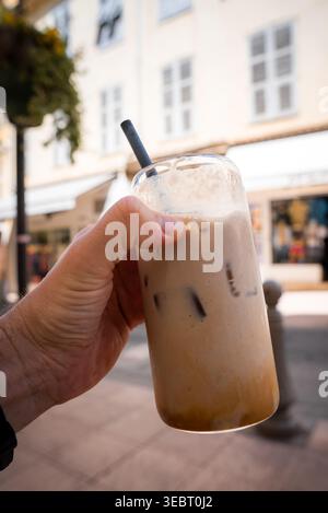 Hand hält Eiskaffee in einer sonnigen Straße in Antibes, Frankreich Stockfoto