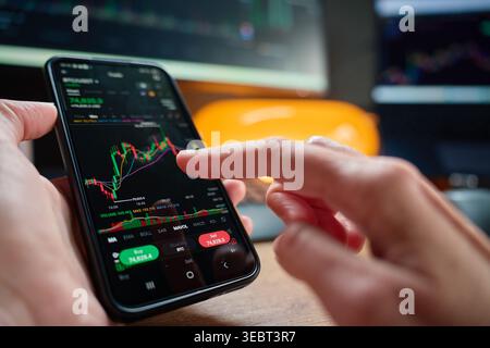 Person, die Marktdiagramm in der Smartphone-Trading-App analysiert. Konzept der Börsenanalyse, Online-Investition, Portfoliomanagement und Mobile Finance. Stockfoto
