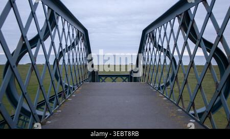 Über die Brücke mit Blick auf das Gras und das Meer Stockfoto
