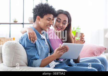 Junge Paare genießen einen gemütlichen Moment zusammen, während sie am Nachmittag ein Tablet zu Hause verwenden Stockfoto