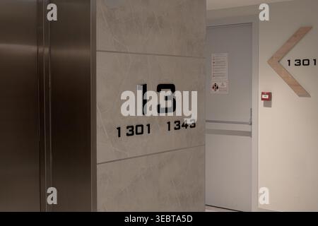 Minimalistischer Innenkorridor mit architektonischen Schildern, Aufzugstüren und Richtungspfeilen Stockfoto