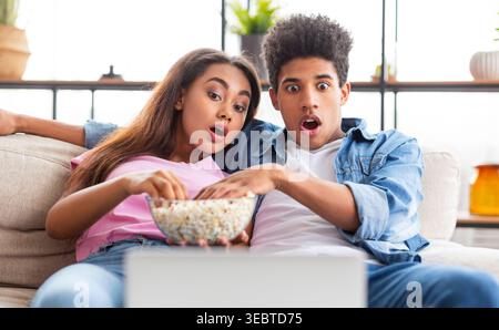 Junges Paar genießt Filmabend zusammen mit Popcorn zu Hause im gemütlichen Wohnzimmer Stockfoto