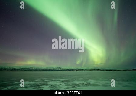 Nordlichter über einer gefrorenen Landschaft im Abisko-Nationalpark, Schweden. Das Eis reflektiert das Licht der Aurora. Stockfoto