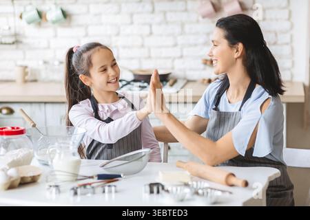 Mutter und Tochter genießen das gemeinsame Backen in einer gemütlichen Küche an einem sonnigen Nachmittag Stockfoto