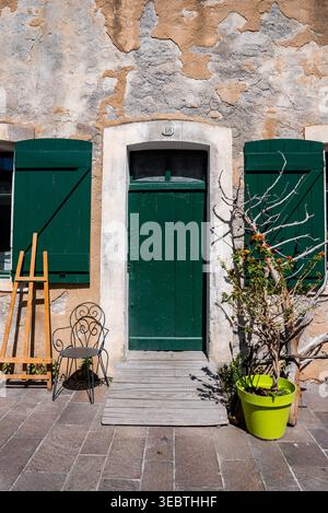 Sonnendurchflutete Steinfassade mit grüner Tür und Fensterläden in Antibes, Frankreich Stockfoto