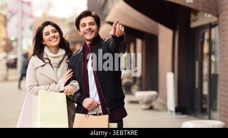 Paare genießen es, gemeinsam einzukaufen, während sie nachmittags eine geschäftige City Street entlang laufen Stockfoto