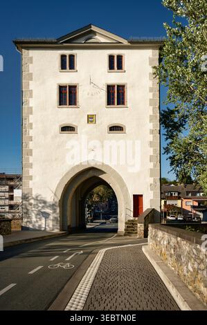 Mittelalterlicher Brückenturm in Limburg mit Sonnenuhr und spitzem Torbogen unter blauem Himmel. Wahrzeichen der deutschen Stadtarchitektur in Hessen Stockfoto