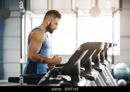Sportlicher Mann, der im Fitnessraum auf dem Laufband läuft Stockfoto