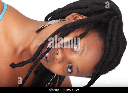 Junge afroamerikanische Frau mit dicken schwarzen Locken und geflochtener Frisur lächelt, während sie in einem blauen Tanktop vor weißem Hintergrund posiert. Stockfoto