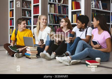 Gruppe von Studenten, die am Nachmittag gemeinsam auf dem Boden in einer Bibliothek studieren Stockfoto