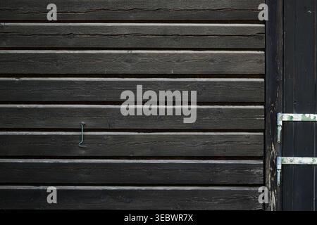 Verwitterte horizontale Holzdielen, die natürliche Alterung und die organische Struktur dunkler, abgenutzter Holzoberflächen zeigen. Stockfoto