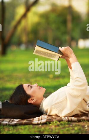 Entspannen Sie sich im Park, während Sie ein Buch an einem sonnigen Tag lesen Stockfoto