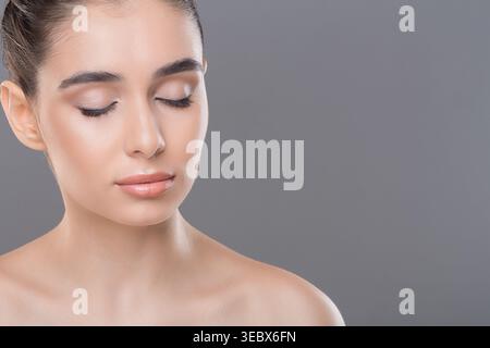 Nahaufnahme einer jungen Frau mit natürlichem Make-up und geschlossenen Augen in einem einfachen Hintergrund Stockfoto