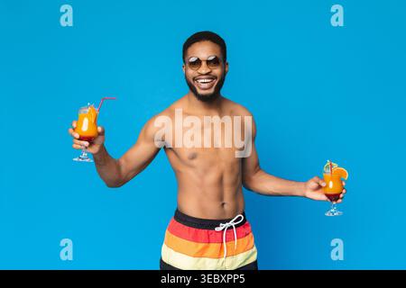 Fröhliche african american guy Holding zwei Sommer cocktails Stockfoto