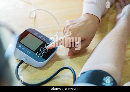 Rückansicht einer älteren Frau, deren Blutdruck von einer Pflegeperson zu Hause gemessen wird. Gesundheitsfürsorge und medizinisches Konzept. Stockfoto