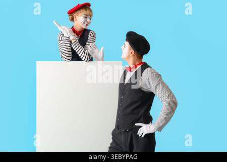 Ein paar Pantomimisten mit leerem Poster auf blauem Hintergrund Stockfoto