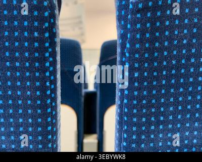 Detailgetreue Aufnahme marineblauer Stoffsitze, die mit hellblauen Quadraten verziert sind, erwecken ein Gefühl von öffentlichem Nahverkehr und Reisen in einer städtischen Umgebung Stockfoto