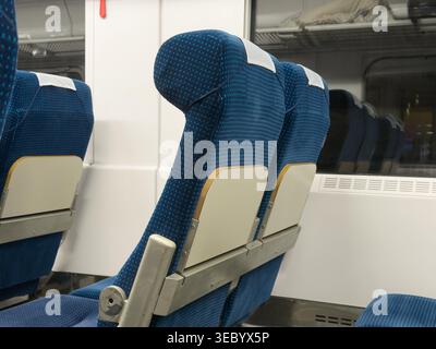 Nahaufnahme der gemusterten blauen Textilpolsterung auf leeren Sitzen im Personenzug mit cremefarbenen Rückenlehnen, die auf Reisen und bequeme tran hindeuten Stockfoto