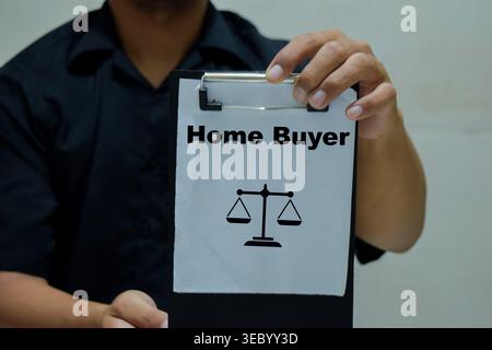 Der Geschäftsmann hält ein Klemmbrett mit dem Namen des Hauskäufers in der Hand. Stockfoto