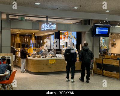 Krakau, Polen - 3. Dezember 2025: Blick auf den McCafe-Schalter am Flughafen, wo Kunden Getränke und Gebäck bestellen und ein Abflugschwein zeigen Stockfoto
