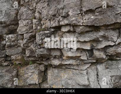 Strukturierter grauer Hintergrund aus sedimentären Steinen, der eine raue, mehrschichtige Mineraloberfläche zeigt. Mit natürlichen geologischen Formationen mit subtilen Erdtönen Stockfoto