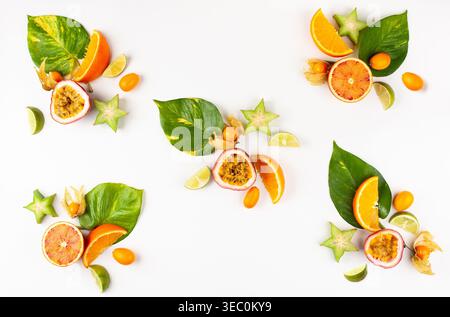 Buntes Muster von ganzen und geschnittenen exotischen Früchten mit tropischen Blättern und Blumen. Sommerkonzept mit Früchten auf weißem Hintergrund. Draufsicht. Stockfoto