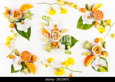 Buntes Muster von ganzen und geschnittenen exotischen Früchten mit tropischen Blättern und Blumen. Sommerkonzept mit Früchten auf weißem Hintergrund. Draufsicht. Stockfoto