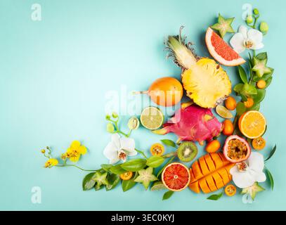 Stillleben mit frisch sortierten exotischen Früchten und Blumen auf blauem Hintergrund. Konzept der gesunden Ernährung mit Früchten und tropischen Blumen. Draufsicht. Stockfoto