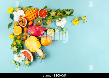Stillleben mit frisch sortierten exotischen Früchten und Blumen auf blauem Hintergrund. Konzept der gesunden Ernährung mit Früchten und tropischen Blumen. Draufsicht. Stockfoto