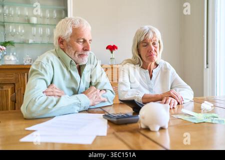 Herausforderungen bei der Altersvorsorge – ein älteres Ehepaar sitzt an einem Tisch und sieht besorgt aus, während es die Finanzdokumente überprüft. Stockfoto