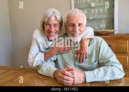 Ein älteres Paar wird in einer freudigen und sicheren Umarmung gefangen genommen, die gesundes Altern und das dauerhafte Glück einer langfristigen Beziehung symbolisiert. Stockfoto