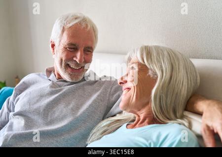 Gesundes Altern und langfristige Sicherheit, ein glückliches Seniorenpaar lächelt und lacht zusammen in einer komfortablen Innenumgebung. Stockfoto