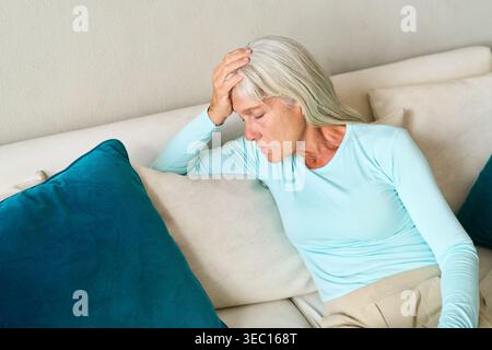 Eine ältere Frau mit Kopfschmerzen oder Migräne, die häufige Gesundheitsprobleme und Erkrankungen im höheren Alter hervorhebt. Stockfoto
