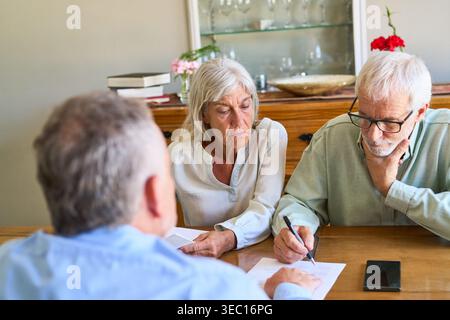 Altersvorsorge und finanzielle Absicherung. Ein Seniorenpaar wird dabei gezeigt, wichtige Dokumente mit einem Finanzberater zu unterzeichnen. Stockfoto