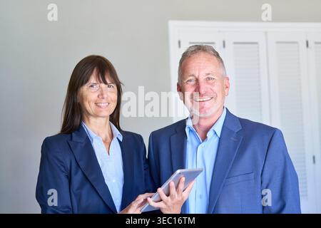 Finanzplanung für Senioren, mit einem professionellen Paar in Geschäftskleidung, das ein digitales Tablet hält. Stockfoto