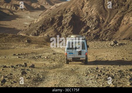 Marsa alam, ägypten 21. april 2026: Weißer Landkreuzer auf einem staubigen, unbefestigten Wüstenweg durch felsiges Sandsteingelände in der Nähe von marsa alam, ägypten — r Stockfoto